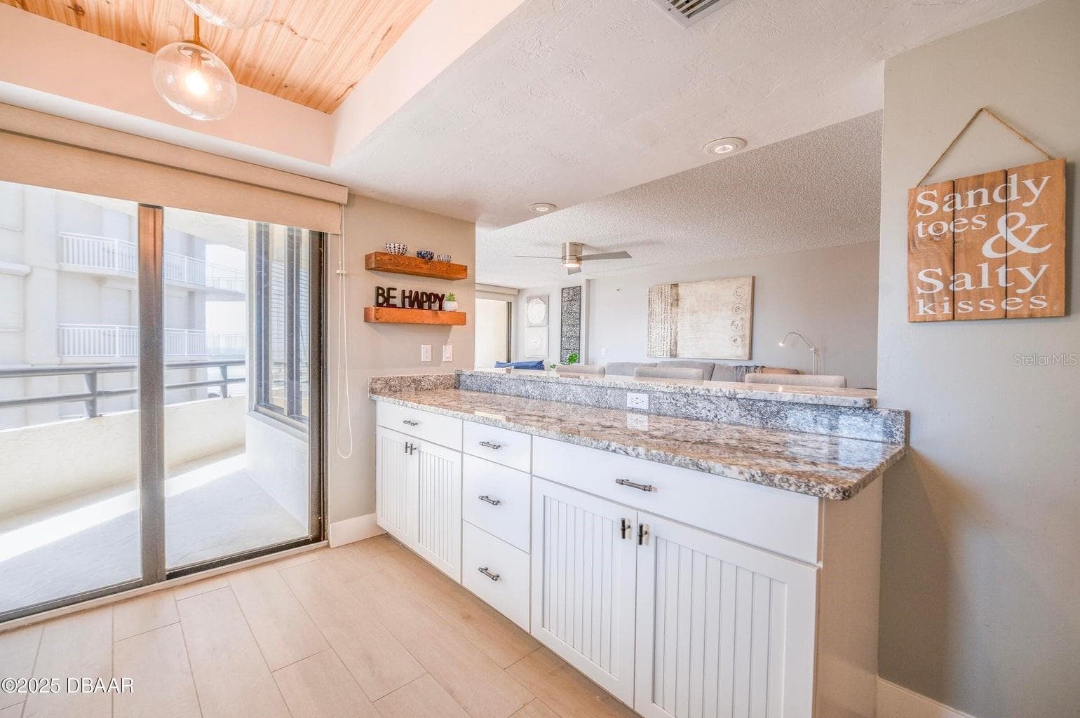 An extended granite breakfast bar provides additional seating and serving space, while ample lower cabinetry offers convenient storage. Sliding glass doors bring natural light into this open and inviting area. - 3855 S ATLANTIC AVE #401, DAYTONA BEACH