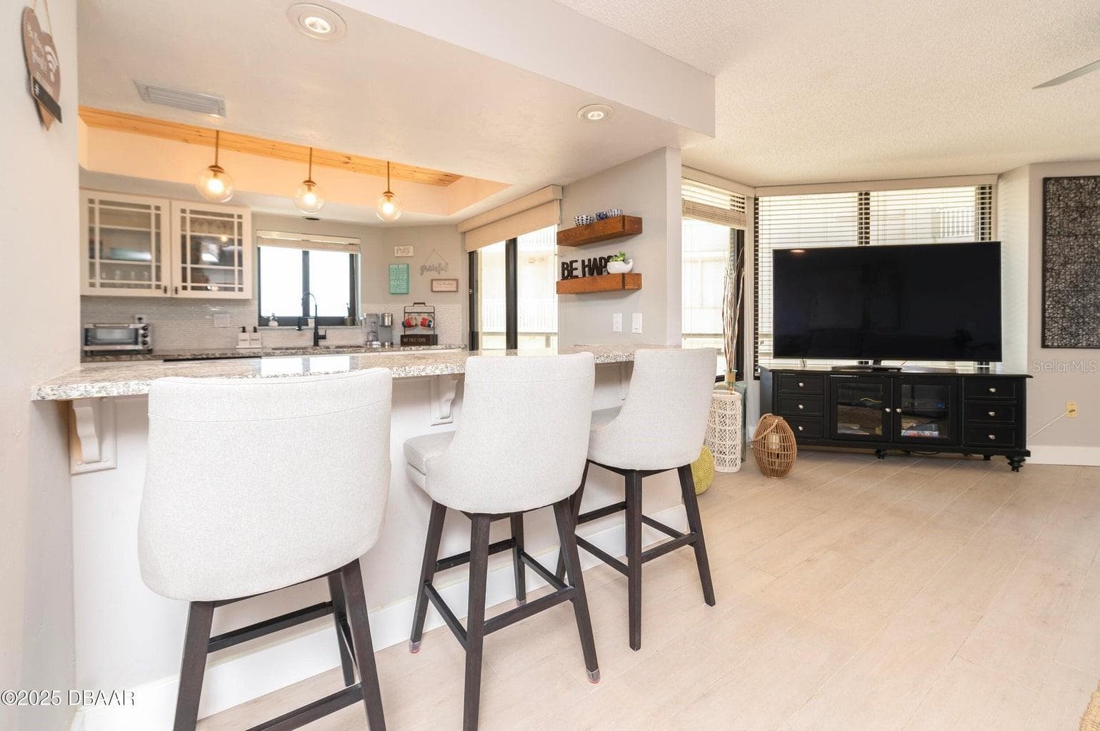 The kitchen flows effortlessly into the living area, with a spacious breakfast bar, contemporary lighting, and large windows creating a comfortable setting for everyday living and entertaining. - 3855 S ATLANTIC AVE #401, DAYTONA BEACH