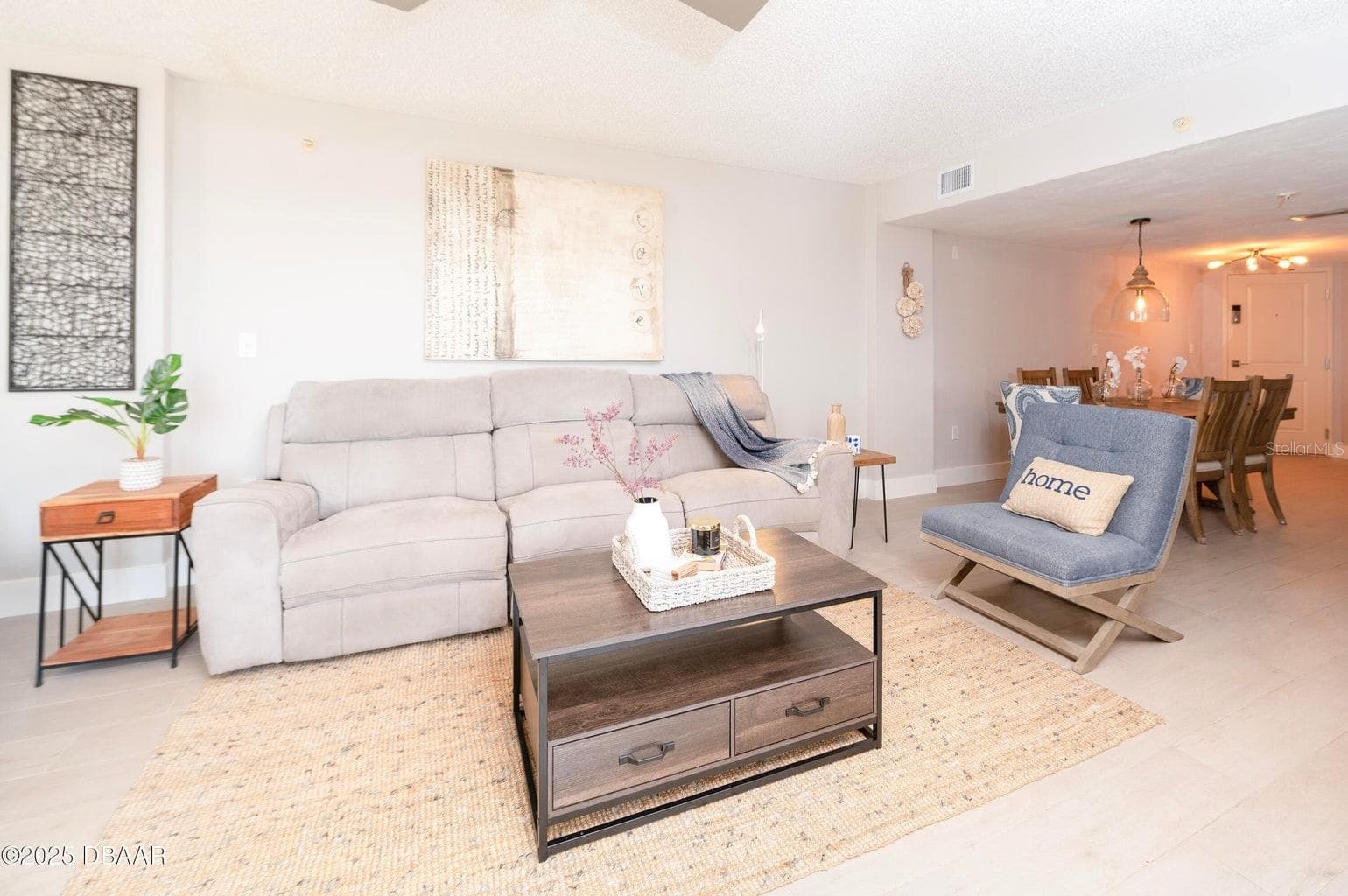 This inviting living room offers a comfortable gathering space with neutral finishes and an open connection to the dining area, ideal for relaxing after a day at the beach. - 3855 S ATLANTIC AVE #401, DAYTONA BEACH