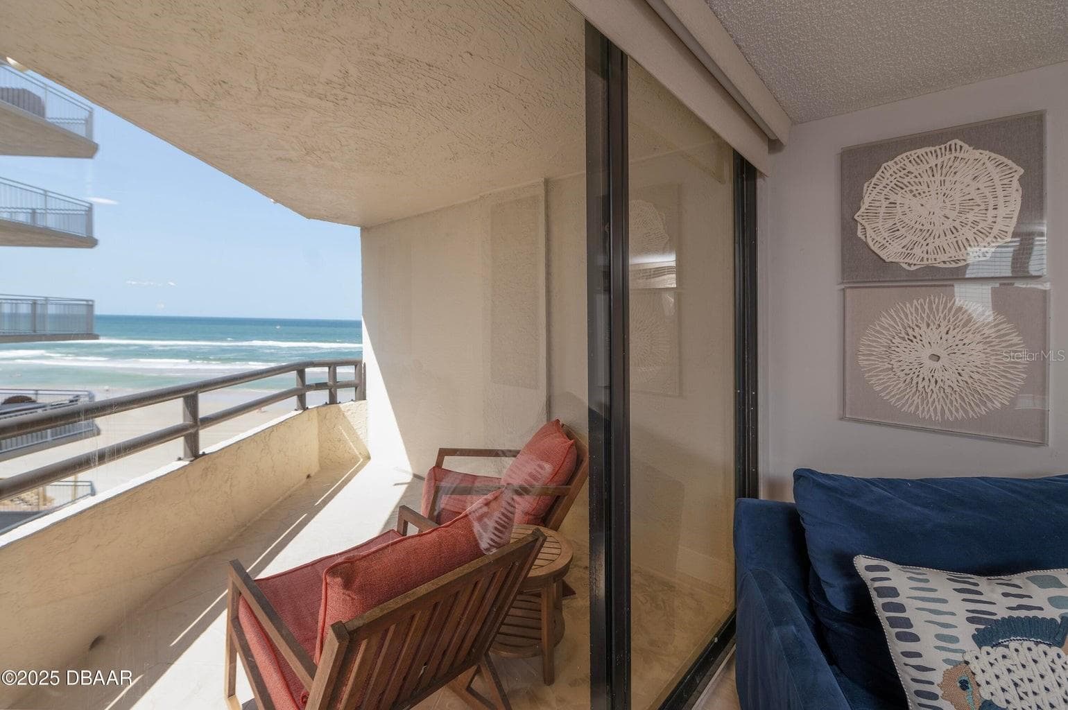 Floor-to-ceiling sliding glass doors connect the living room to the covered oceanfront balcony, offering an effortless transition between indoor comfort and outdoor relaxation. - 3855 S ATLANTIC AVE #401, DAYTONA BEACH