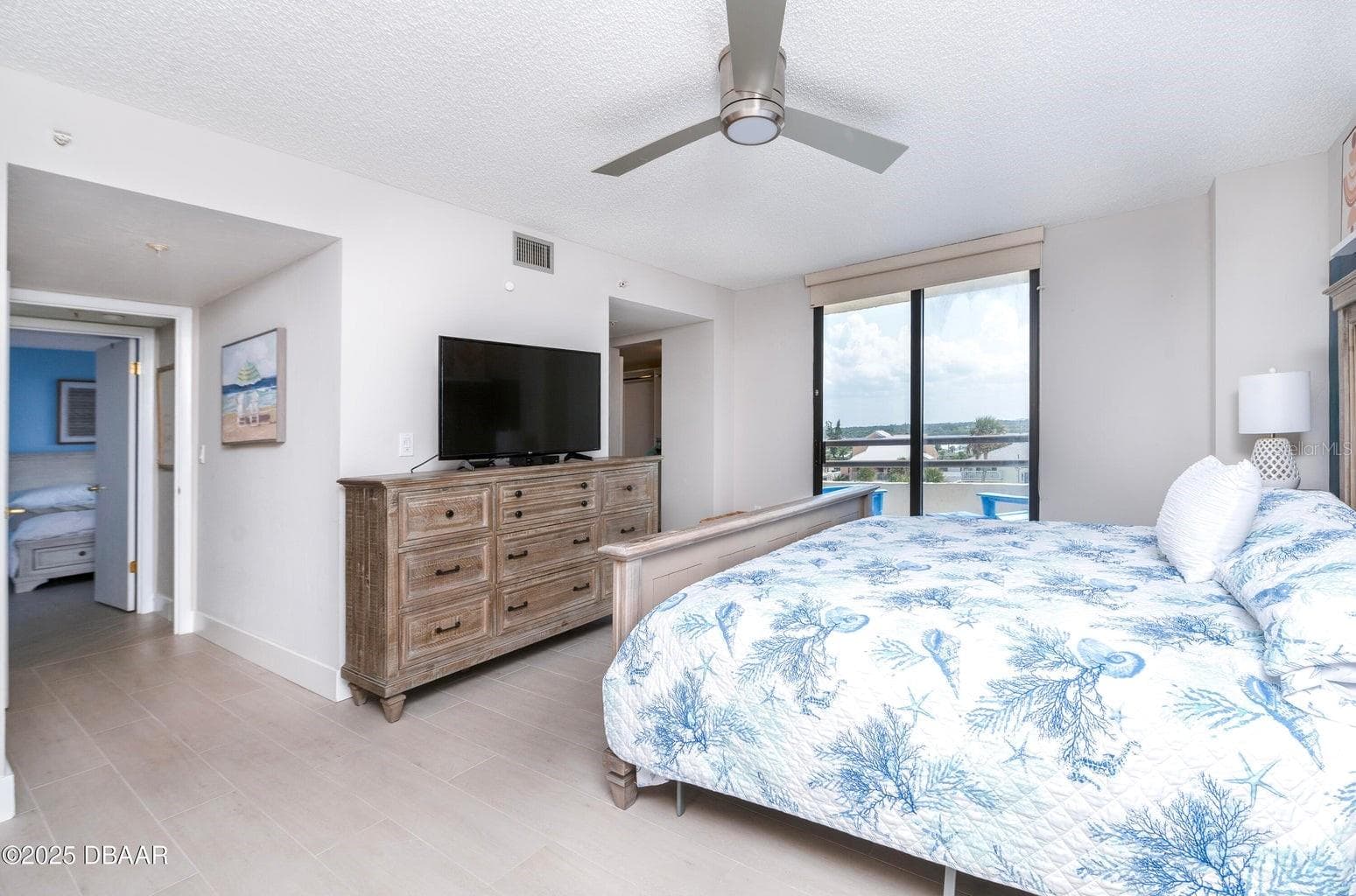 Another view of the generously sized primary bedroom showcases abundant natural light, neutral finishes, and direct balcony access, creating a comfortable coastal retreat. - 3855 S ATLANTIC AVE #401, DAYTONA BEACH