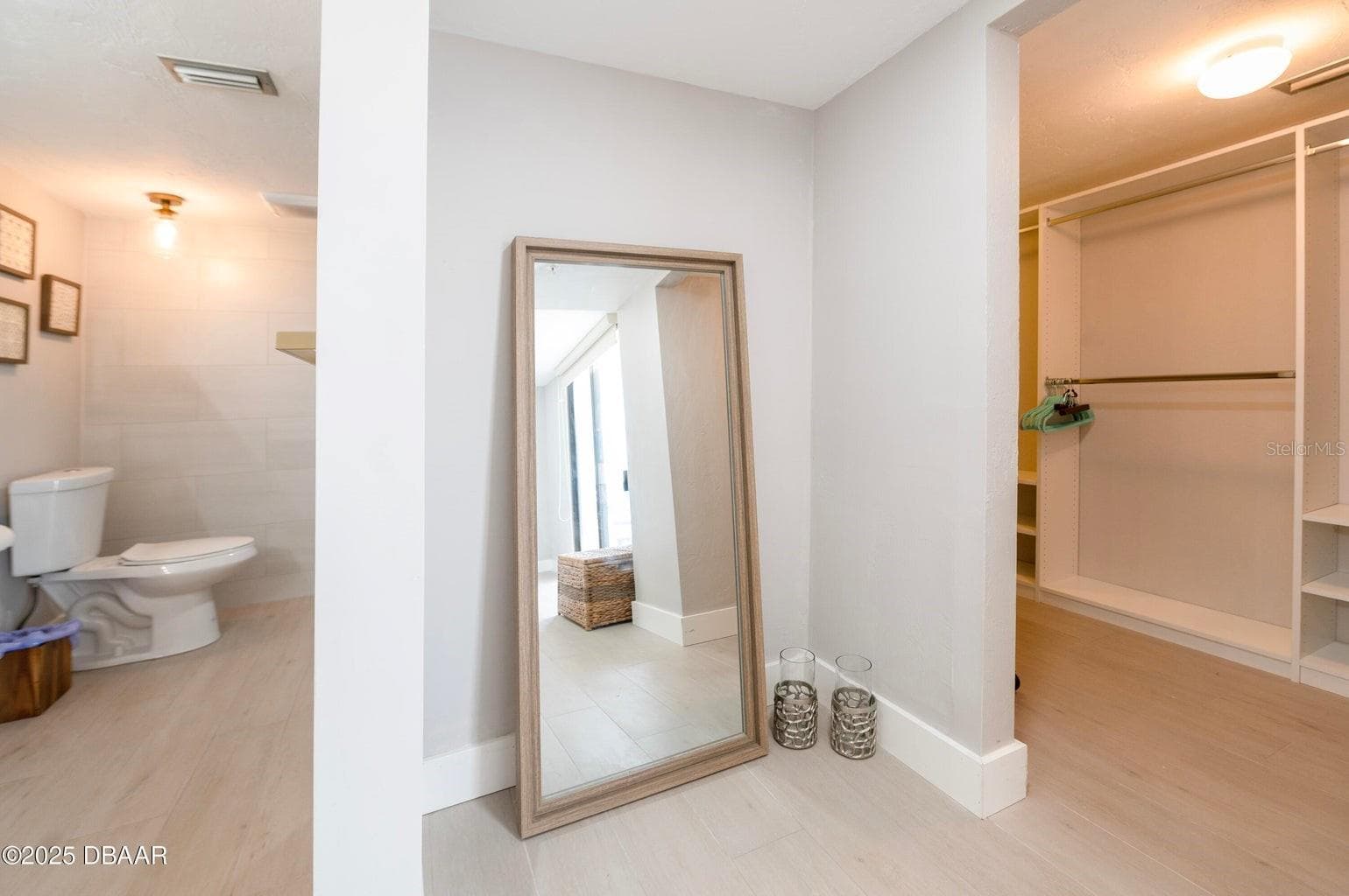 Enjoy a dedicated dressing area with an open closet featuring hanging space and built-in shelving, conveniently positioned near the primary bathroom. - 3855 S ATLANTIC AVE #401, DAYTONA BEACH