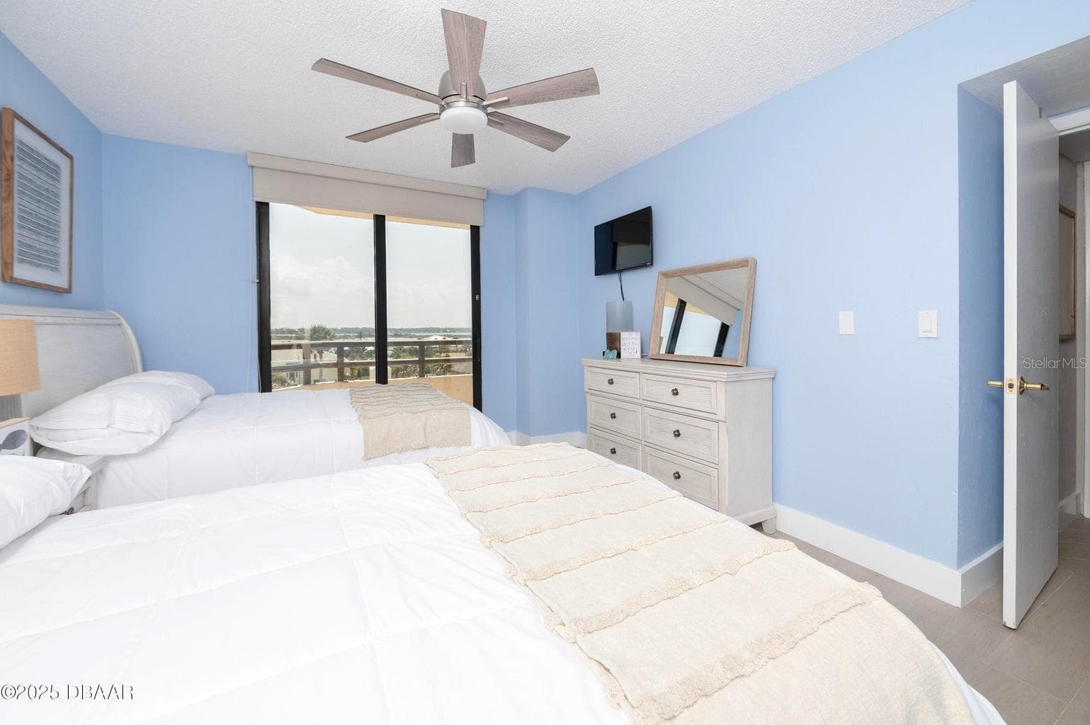 The guest bedroom offers sliding glass doors opening to a private balcony with inland views, allowing natural light to fill the room while extending the living space outdoors. - 3855 S ATLANTIC AVE #401, DAYTONA BEACH
