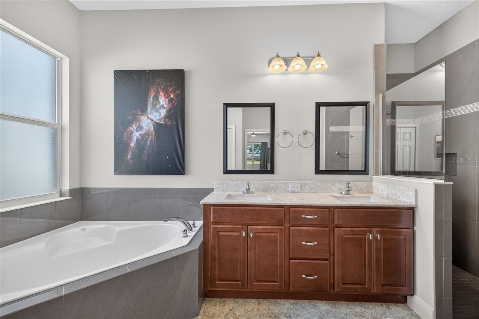 Dual vanity sinks and generous wood cabinetry provide abundant storage and counter space for effortless morning routines. - 2444 PAWTUCKET PASS, MOUNT DORA
