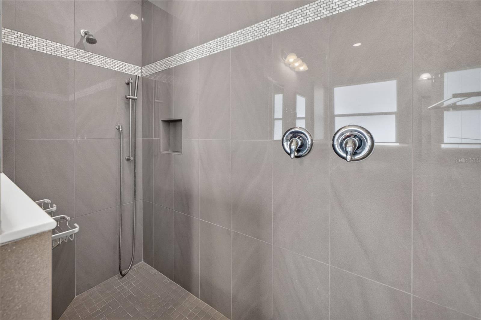 Floor-to-ceiling custom tilework and an accent detail wall give the walk-in shower a striking, spa-like feel. - 2444 PAWTUCKET PASS, MOUNT DORA