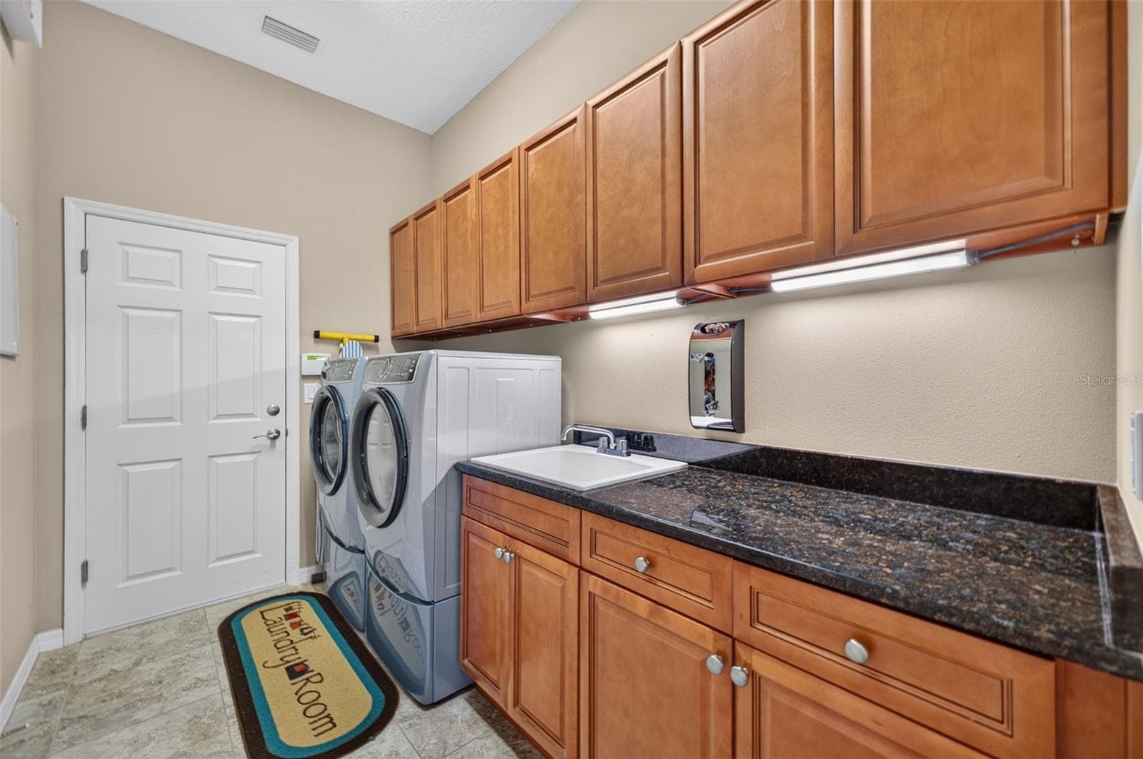 Equipped with rich granite counters, a built-in utility sink, and abundant cabinet storage, this interior laundry room doubles as a convenient drop zone with direct garage entry. - 2444 PAWTUCKET PASS, MOUNT DORA