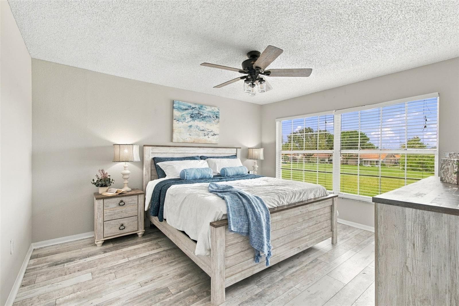 Spacious Primary Bedroom with Views of the Golf Course. All furniture in this room will convey with the sale should the Buyer want it! Note: Bedding, lamps, picture and accessories are staged and not included in sale - Only furniture - 4210 CADDIE DR E #202, BRADENTON