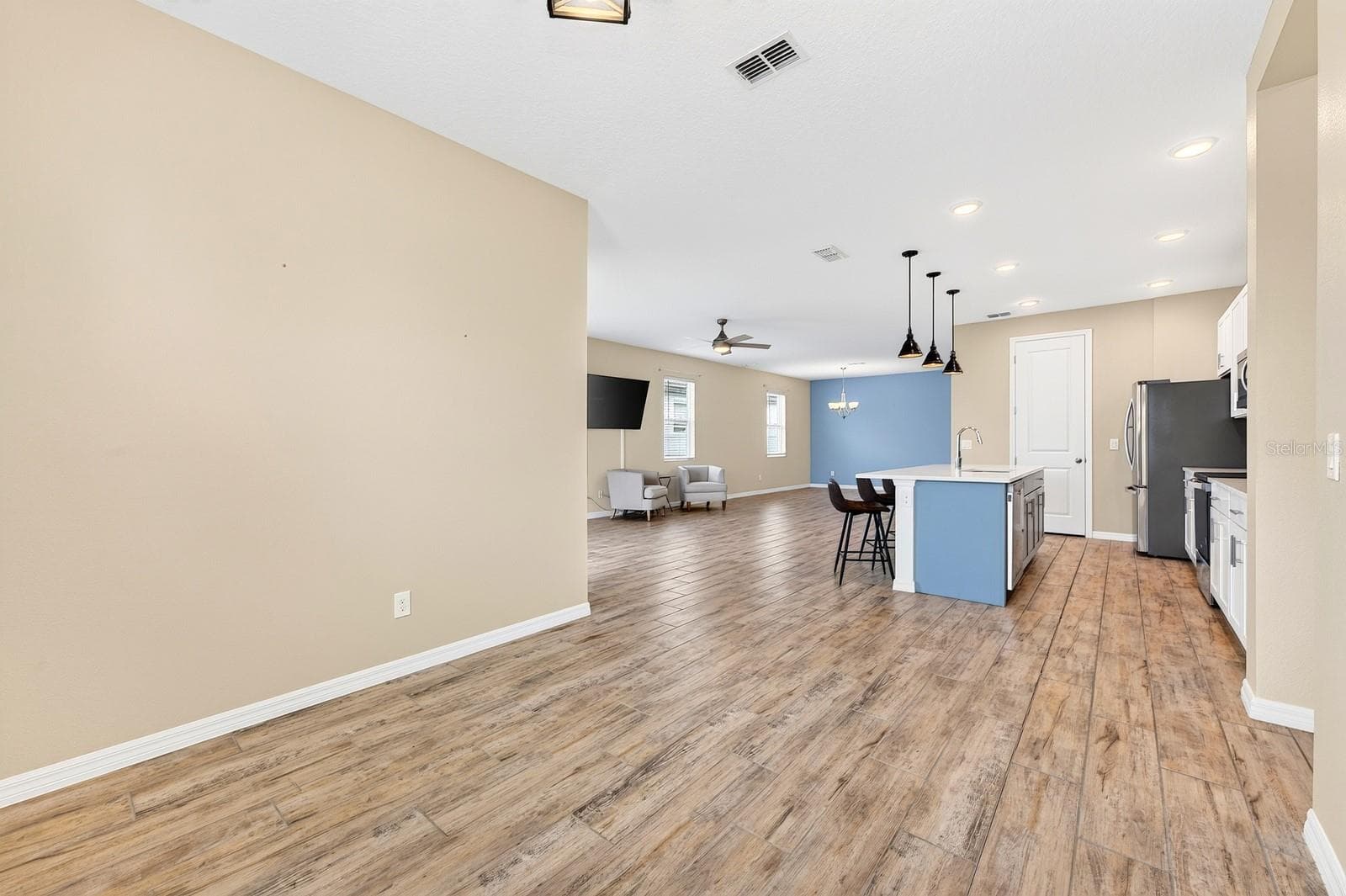 This is a look from the breakfast nook across the open-air family space and porcelain wood-looking tile to join the spaces - 880 LIVESTOCK LOOP, ST CLOUD