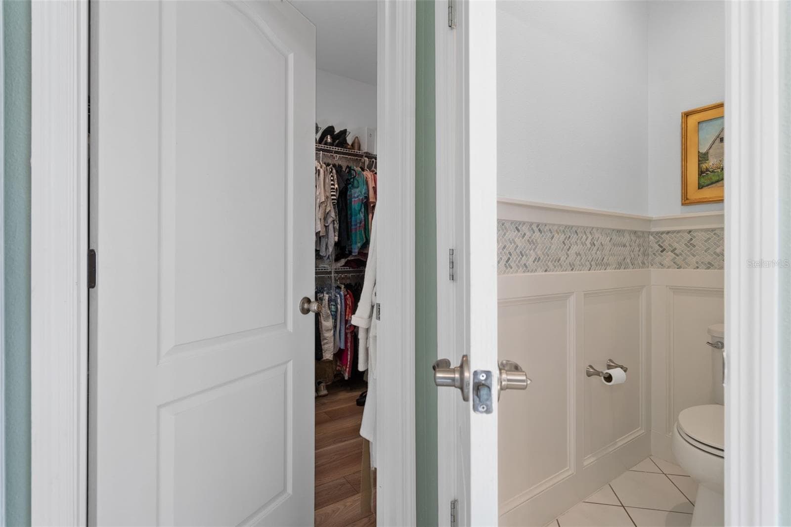 The Primary En-Suite Water Closet offers a Custom Wall Treatment. The walk-in Closet offers plenty of space and LVP flooring. - 1038 TIMBERVALE TRL, CLERMONT