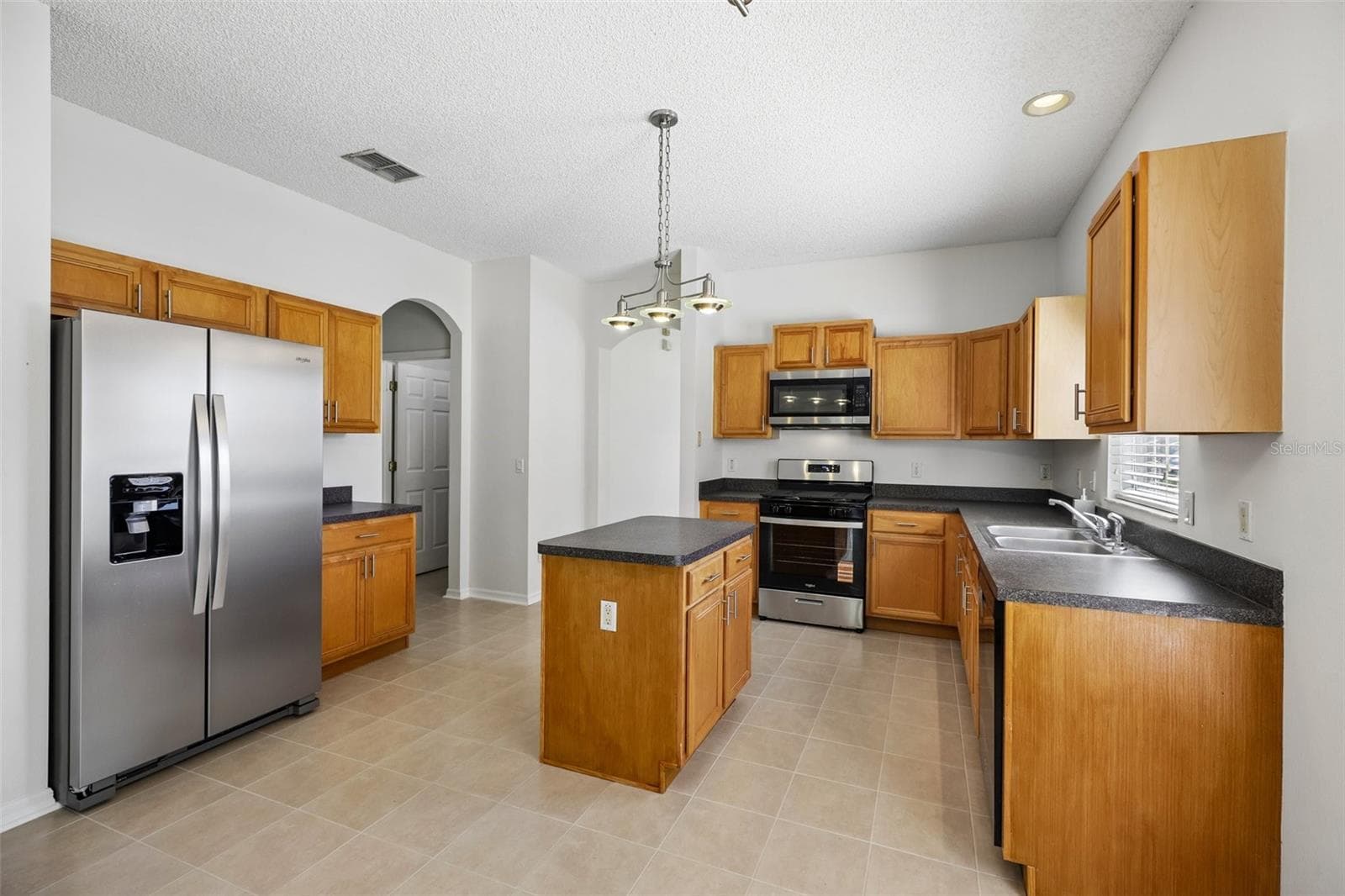 A GRACEFUL ARCHED DOORWAY opens to the Kitchen and Family Room, creating a natural flow between the home's main gathering spaces. - 1806 ANNA CATHERINE DR, ORLANDO