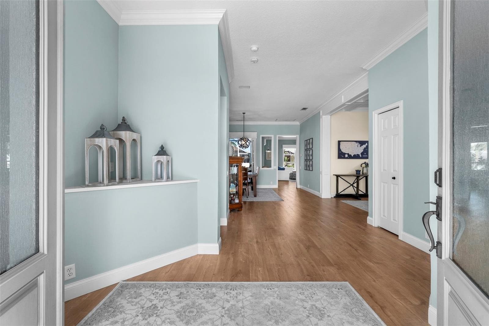 A welcoming entry with soft coastal colors, crown molding, and warm engineered flooring sets the tone for the home. - 4739 COMPASS DR, BRADENTON