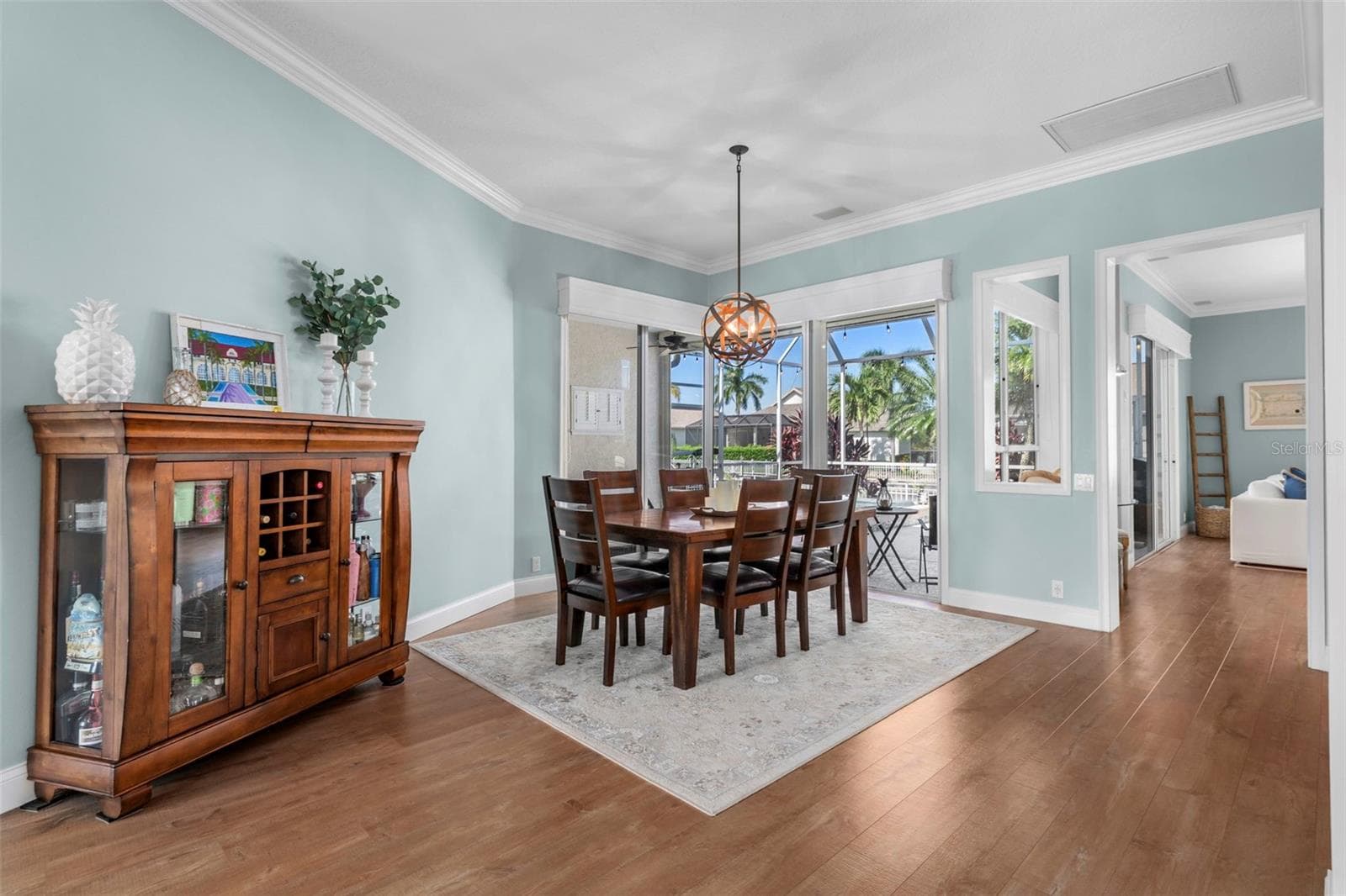 An airy dining space with crown molding, warm flooring, and an easy connection to outdoor entertaining. - 4739 COMPASS DR, BRADENTON