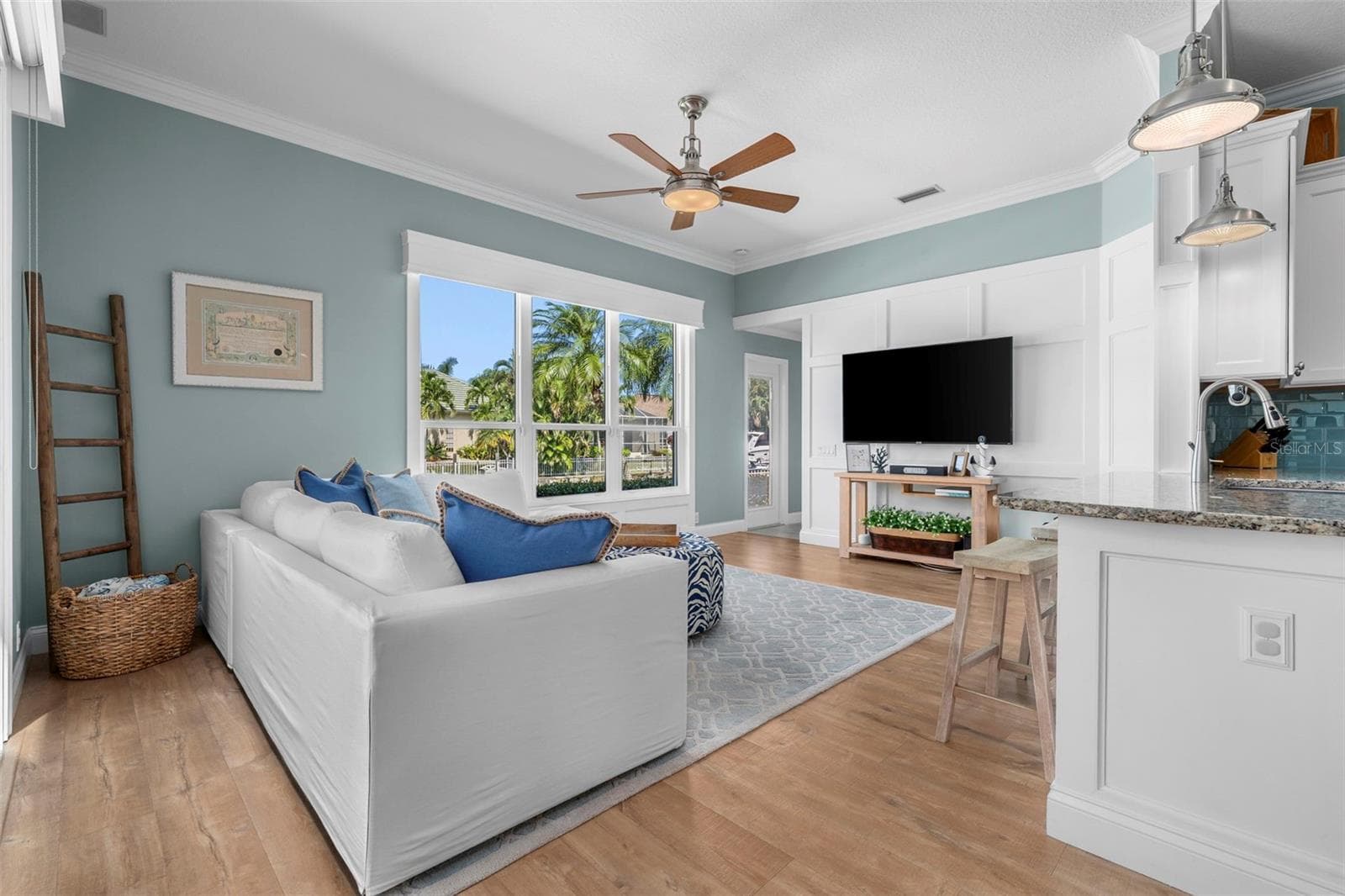 Natural light, waterfront views, and a board-and-batten accent wall bring relaxed coastal style to the living room. - 4739 COMPASS DR, BRADENTON