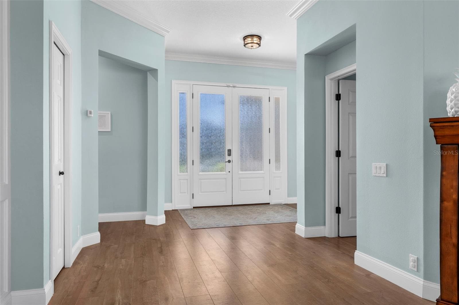 A glass-paneled front entry welcomes natural light, while crown molding and warm flooring create a polished first impression. - 4739 COMPASS DR, BRADENTON