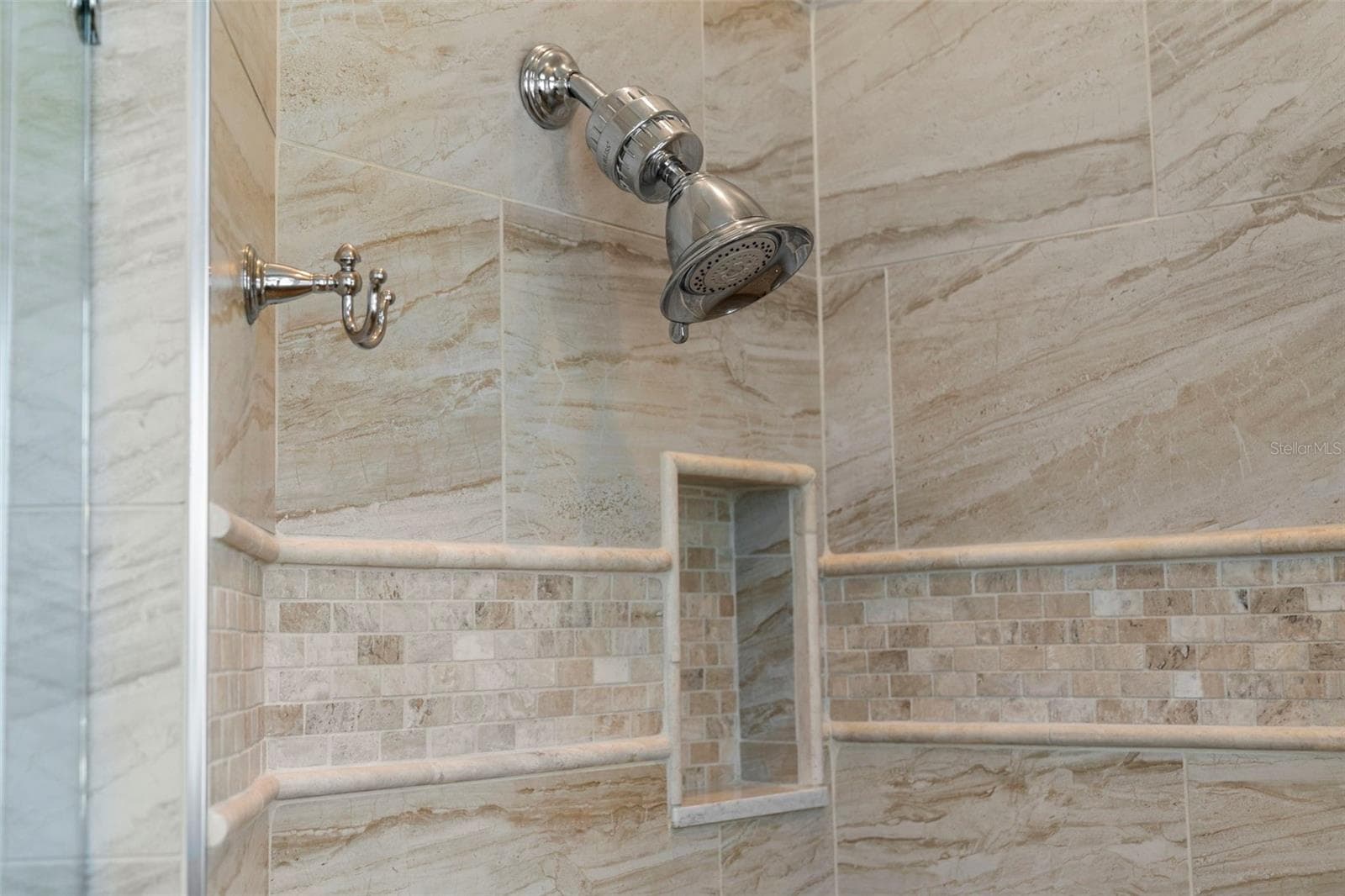 Decorative tilework, polished fixtures, and a recessed niche give the shower a beautifully finished look. - 4739 COMPASS DR, BRADENTON