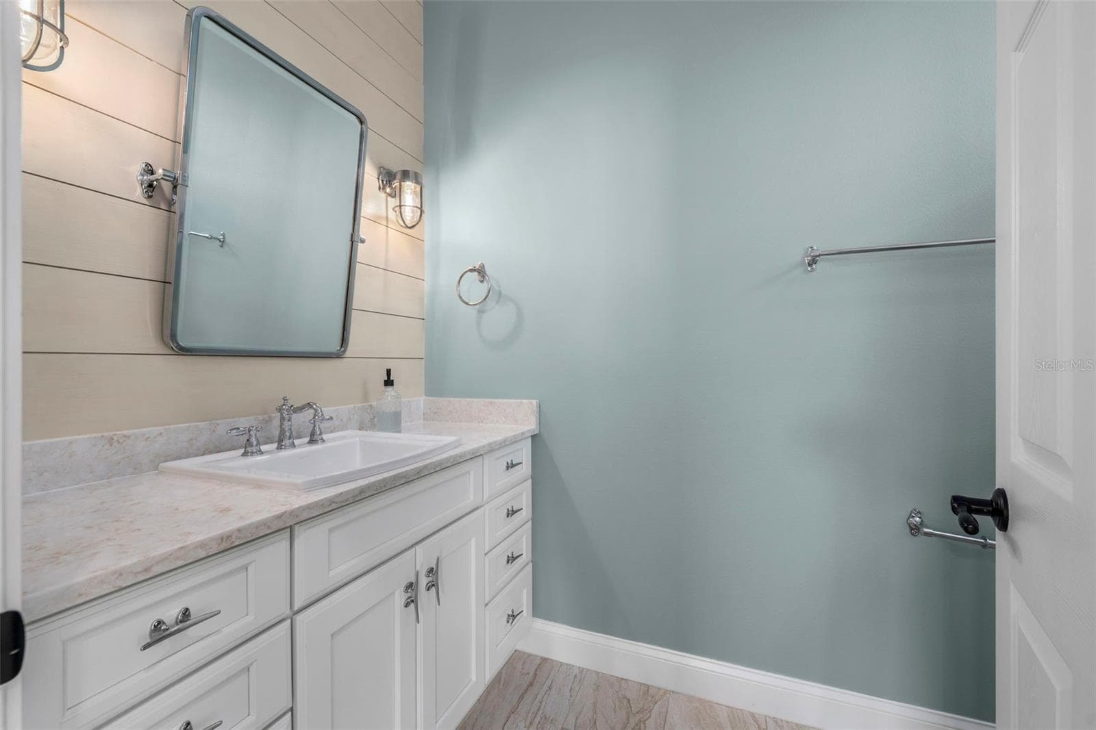 Shiplap accents, nautical-inspired lighting, and a generous vanity bring coastal charm to the renovated guest bath. - 4739 COMPASS DR, BRADENTON