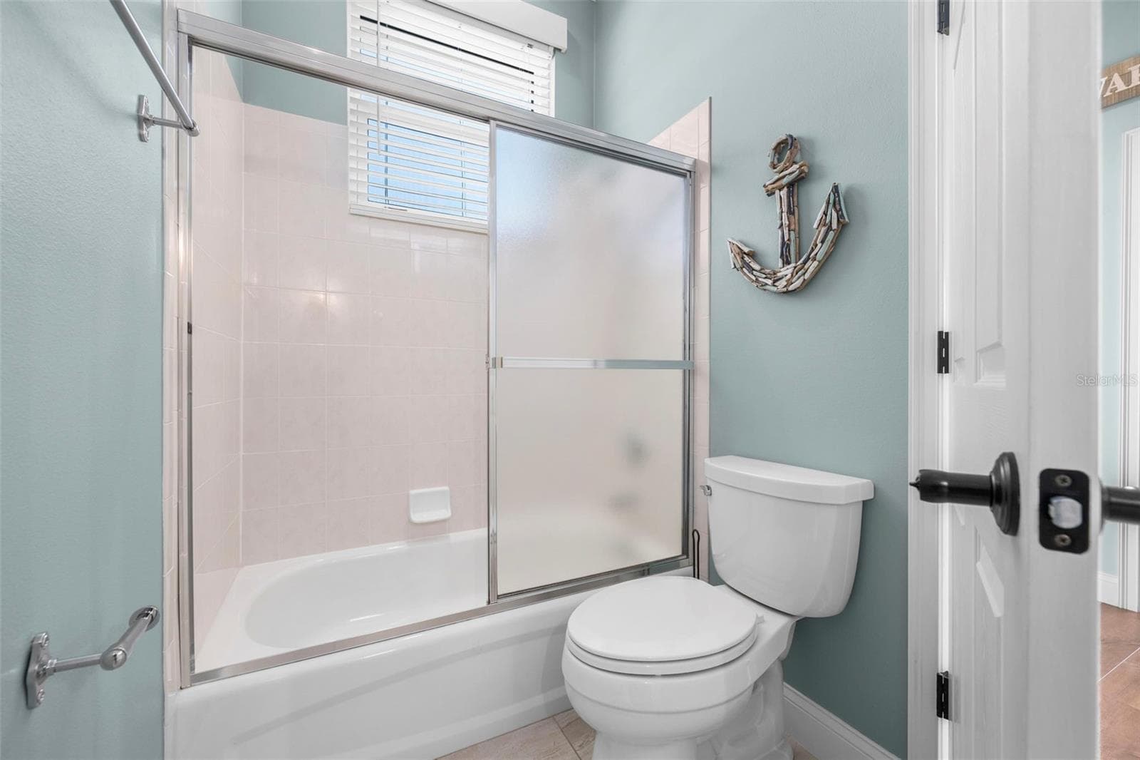 A tub-and-shower combination and soft coastal colors create a bright, welcoming space - 4739 COMPASS DR, BRADENTON