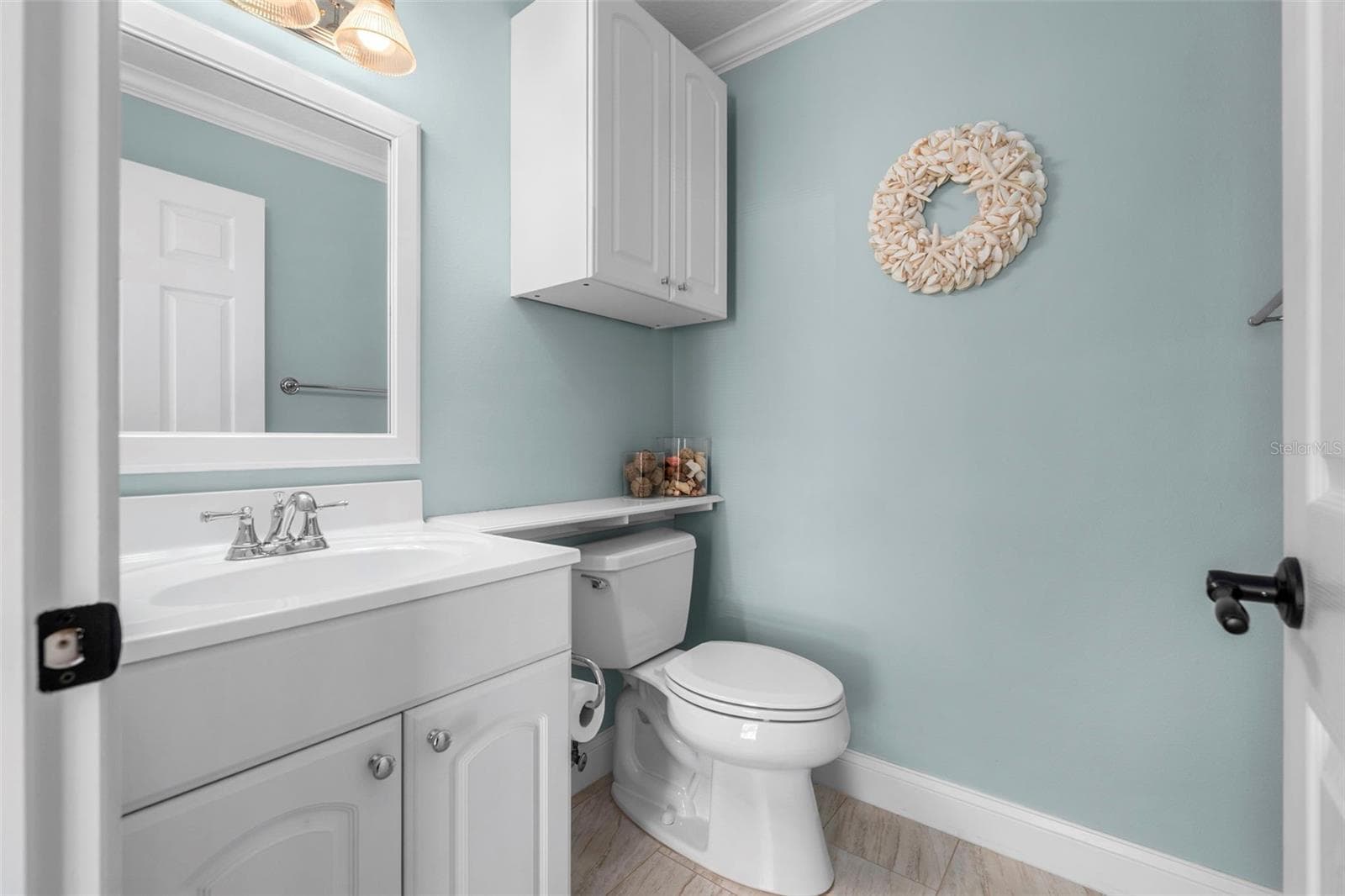 White cabinetry, crown molding, and soothing blue walls give this convenient half bath a polished finish. - 4739 COMPASS DR, BRADENTON