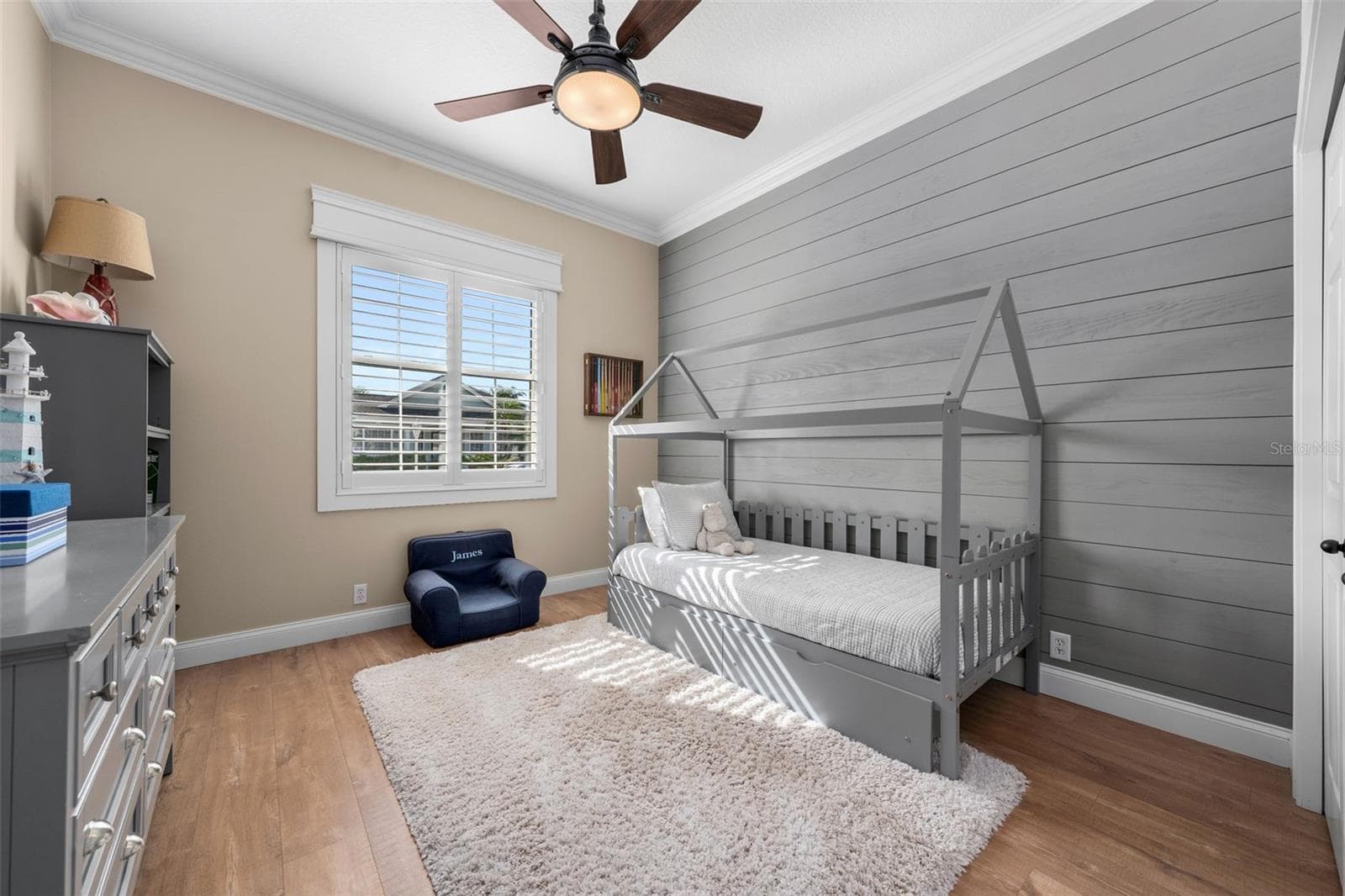 A shiplap feature wall adds character to this bright bedroom, complete with plantation shutters and crown molding. - 4739 COMPASS DR, BRADENTON