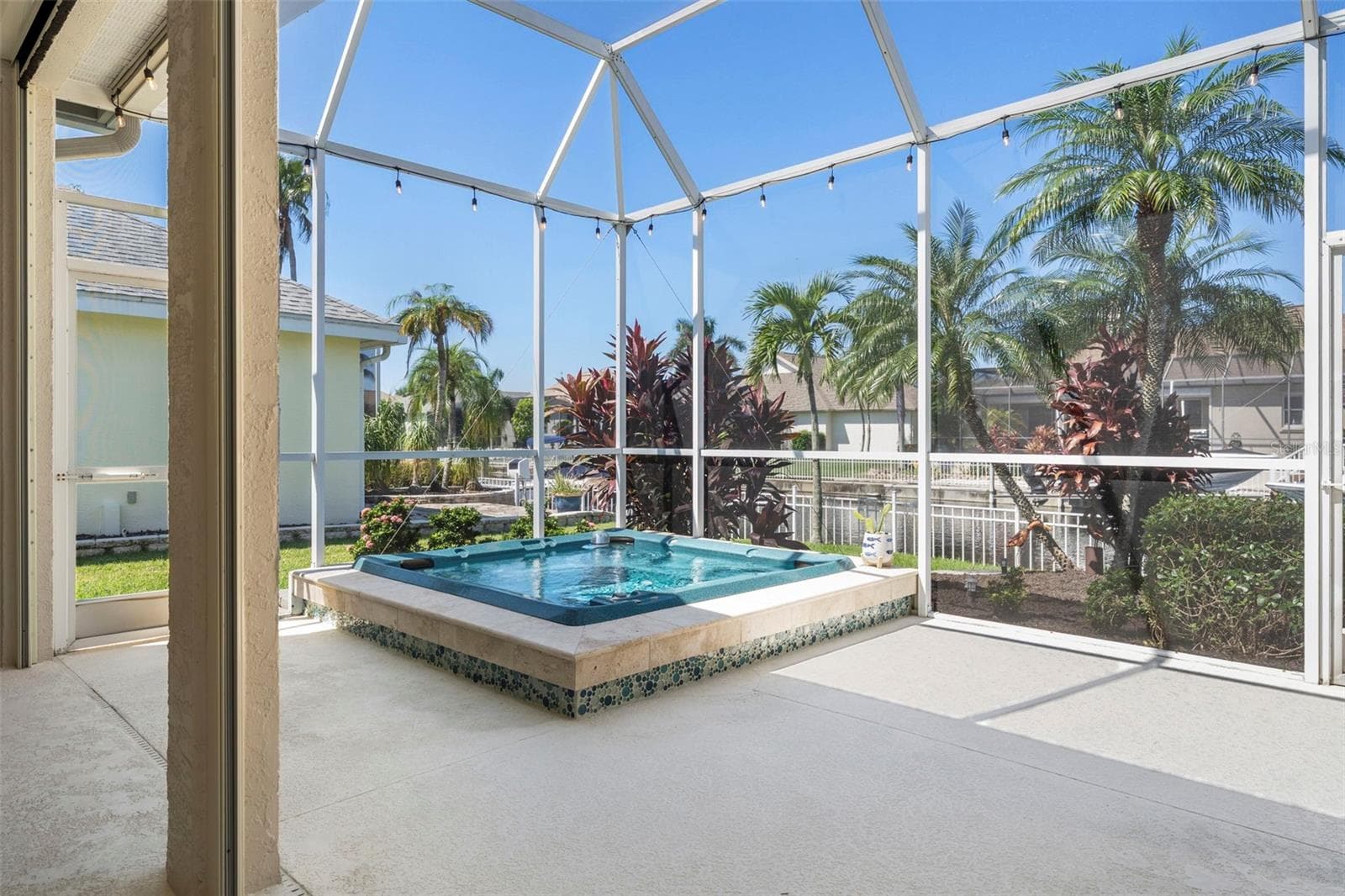 Enjoy a relaxing soak beneath the open sky, with a screened enclosure and tropical surroundings. - 4739 COMPASS DR, BRADENTON