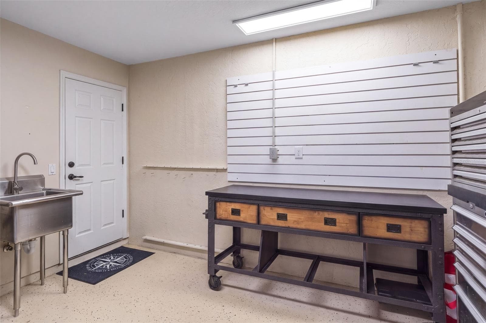 A dedicated garage work area with a utility sink and wall-mounted storage provides a practical spot for projects and organizing gear. - 4739 COMPASS DR, BRADENTON