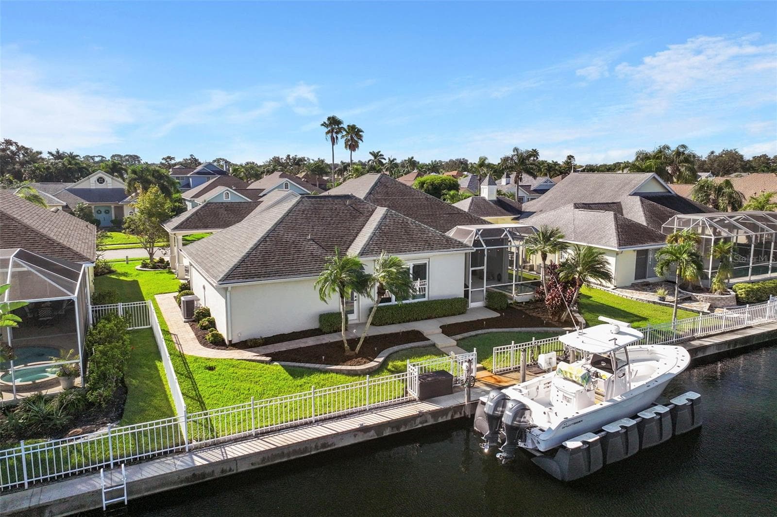 An overhead view showcases the home’s canal setting, screened lanai, and private dock just beyond the backyard. - 4739 COMPASS DR, BRADENTON