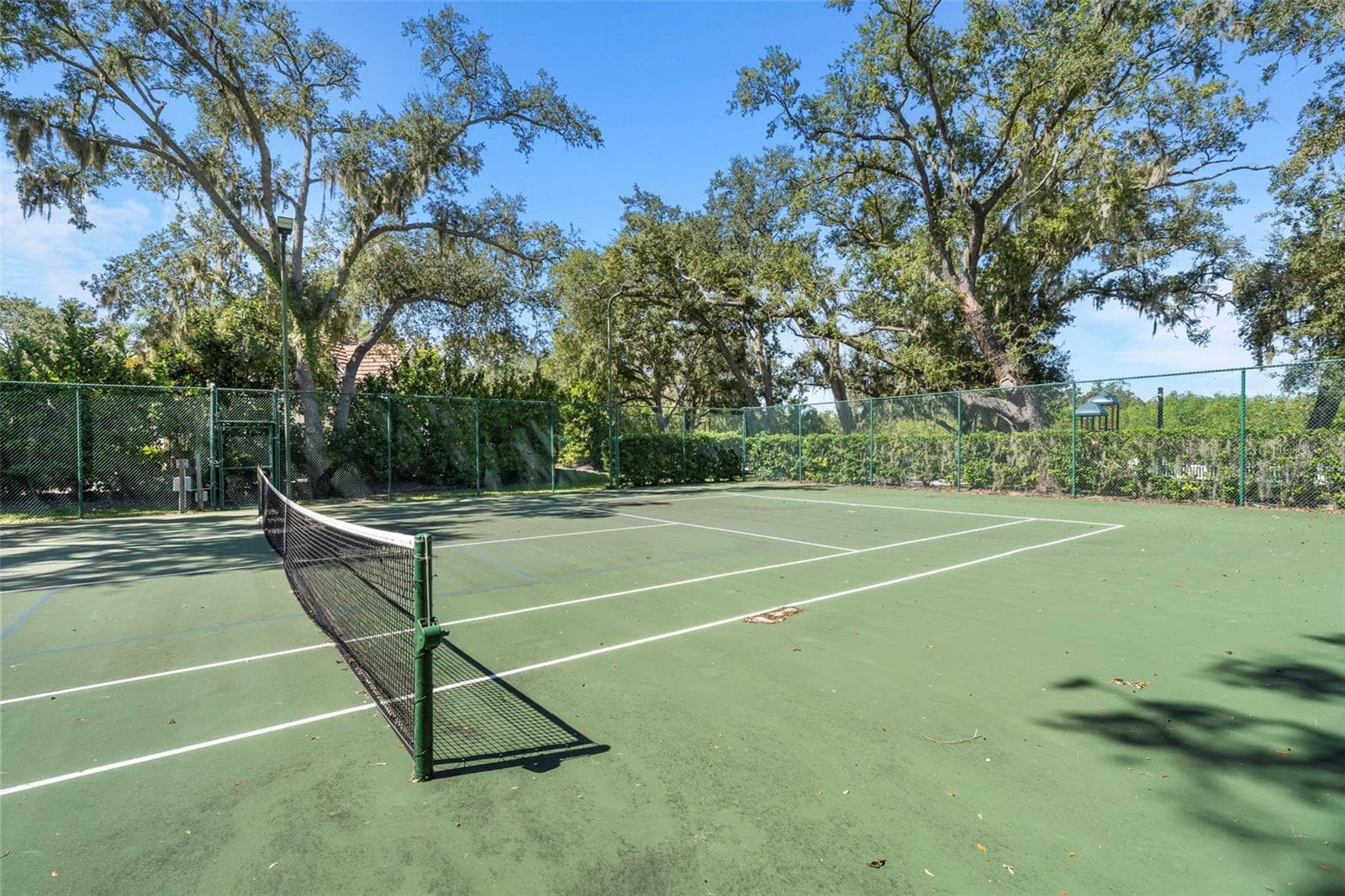 Enjoy a friendly match on the community tennis court, surrounded by mature trees and greenery. - 4739 COMPASS DR, BRADENTON