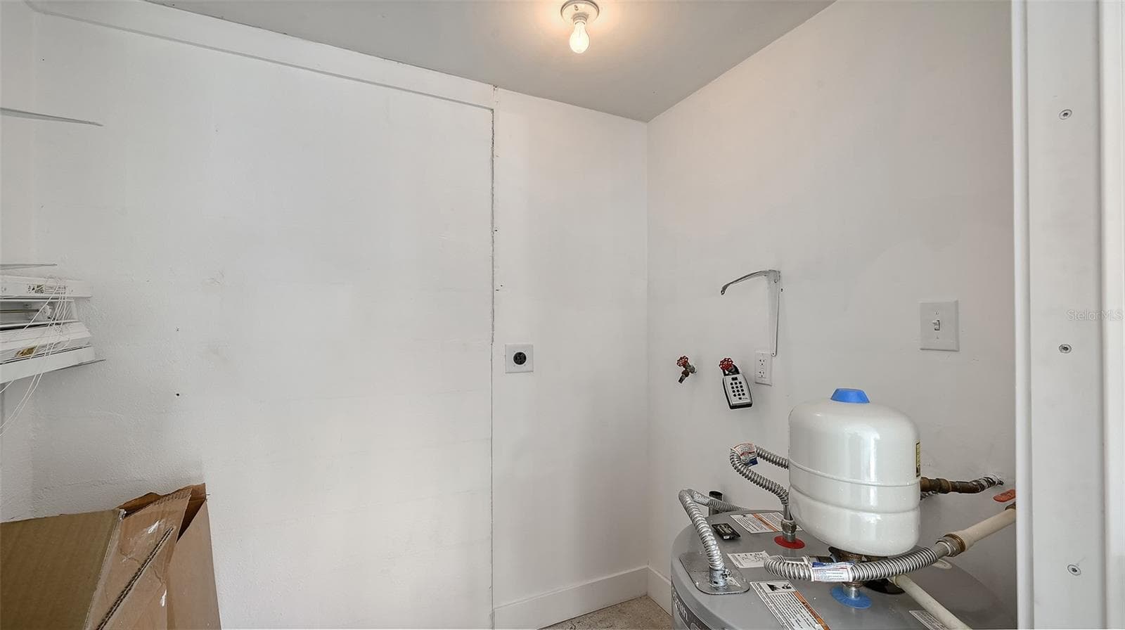 The storage room behind the carport with the new water heater and previous washer/dryer hookup. - 693 SPANISH DR N #24, LONGBOAT KEY