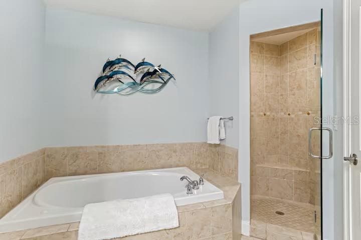 Primary ensiut bathroom with large soaking tub, walk in shower, and private water closet. - 100 BAYSIDE DR #101, CLEARWATER