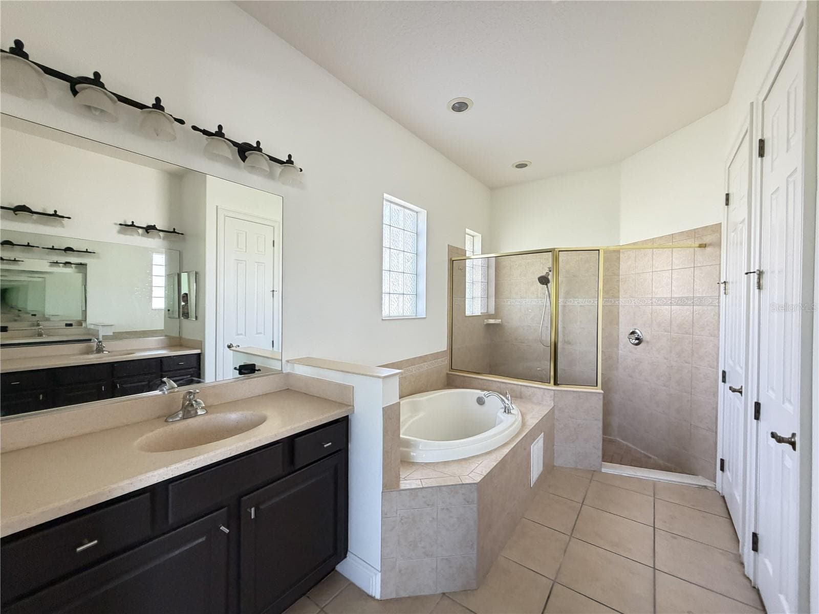 Primary bath with soaking tub, tiled shower, and separate sink vanities. - 39539 HARBOR HILLS BLVD, LADY LAKE