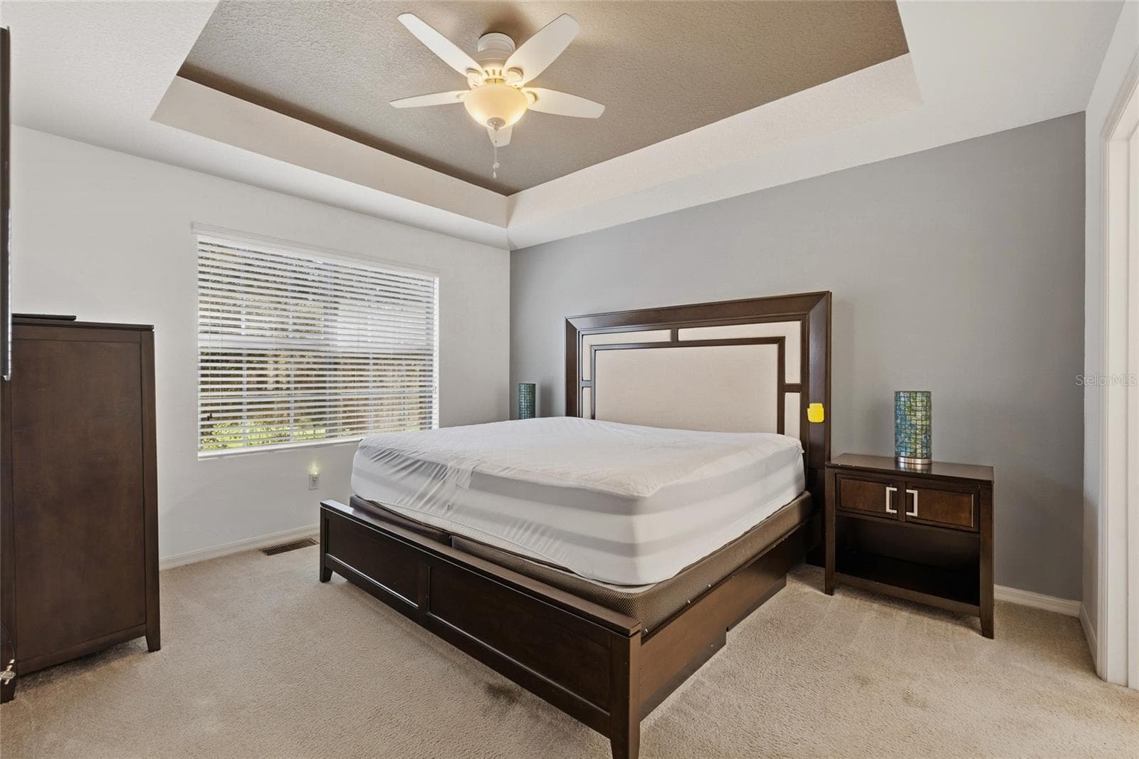 Primary bedroom featuring ceiling fan, accent ceiling with an ensuite bathroom - 15613 BOGGY OAK CIR #110A, WINTER GARDEN