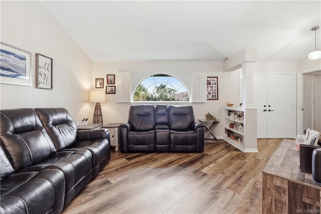 SPACIOUS LIVING ROOM- Comfortable living room featuring newer luxury vinyl flooring, vaulted ceiling & a beautiful arched window w/plantation shutters. - 1436 N CHERRY POP DR, HERNANDO