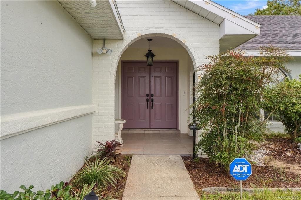 COVERED FRONT ENTRANCE- Inviting covered entrance featuring an attractive brick archway, double entry doors & decorative landscaping. - 1436 N CHERRY POP DR, HERNANDO