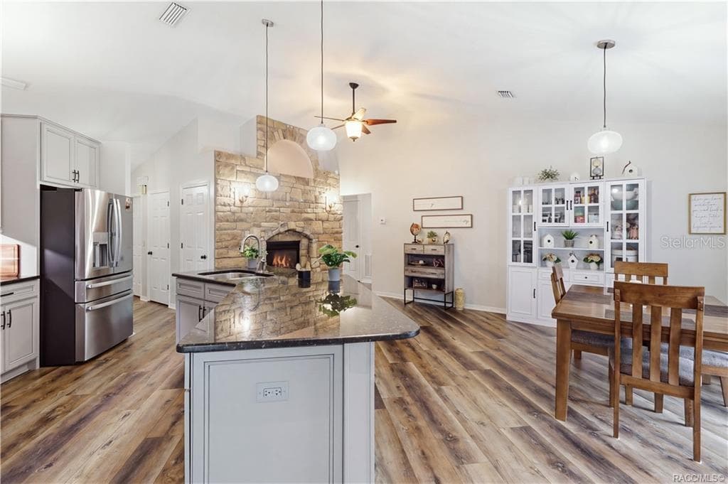 KITCHEN & DINING VIEW- Spacious kitchen & dining layout featuring a large granite island, vaulted ceilings & striking stone-accented fireplace. - 1436 N CHERRY POP DR, HERNANDO