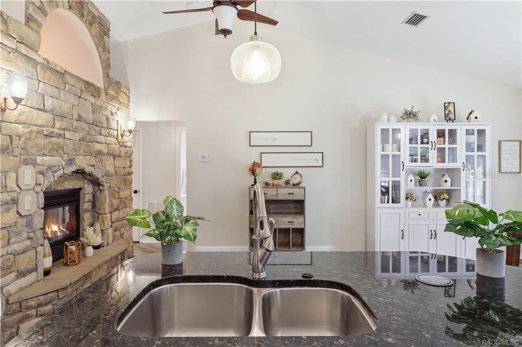KITCHEN & FIREPLACE VIEWOpen kitchen showcasing the granite island, vaulted ceilings, stone-accented fireplace & adjoining dining area. - 1436 N CHERRY POP DR, HERNANDO