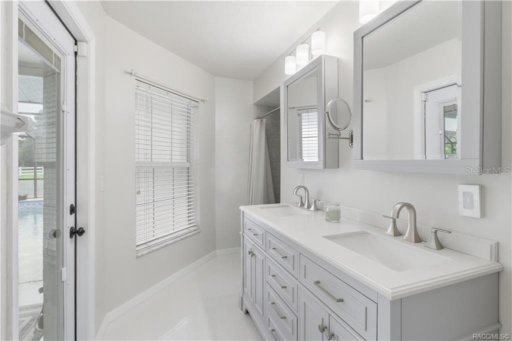 Primary Bathroom – Light & bright primary bathroom featuring a double-sink vanity, updated cabinetry, generous countertop space & direct access to the screened pool area. - 1436 N CHERRY POP DR, HERNANDO