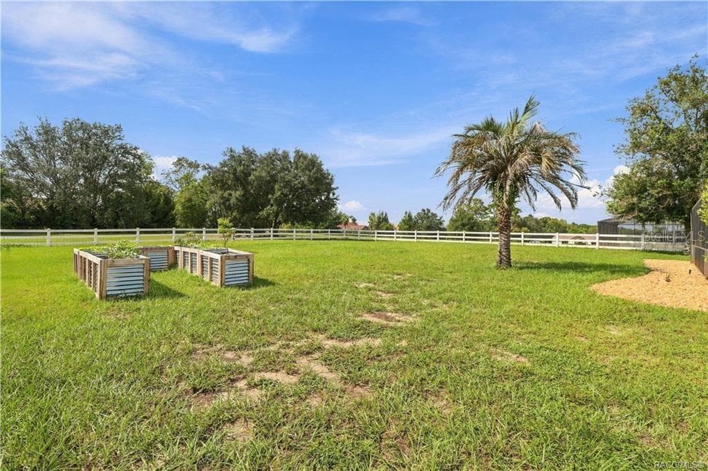 Backyard & Garden Area – Enjoy the wide-open backyard featuring attractive WHITE RAIL FENCING, raised garden beds & a palm tree. Plenty of room to enjoy gardening, outdoor activities or simply relaxing in the Florida sunshine! - 1436 N CHERRY POP DR, HERNANDO