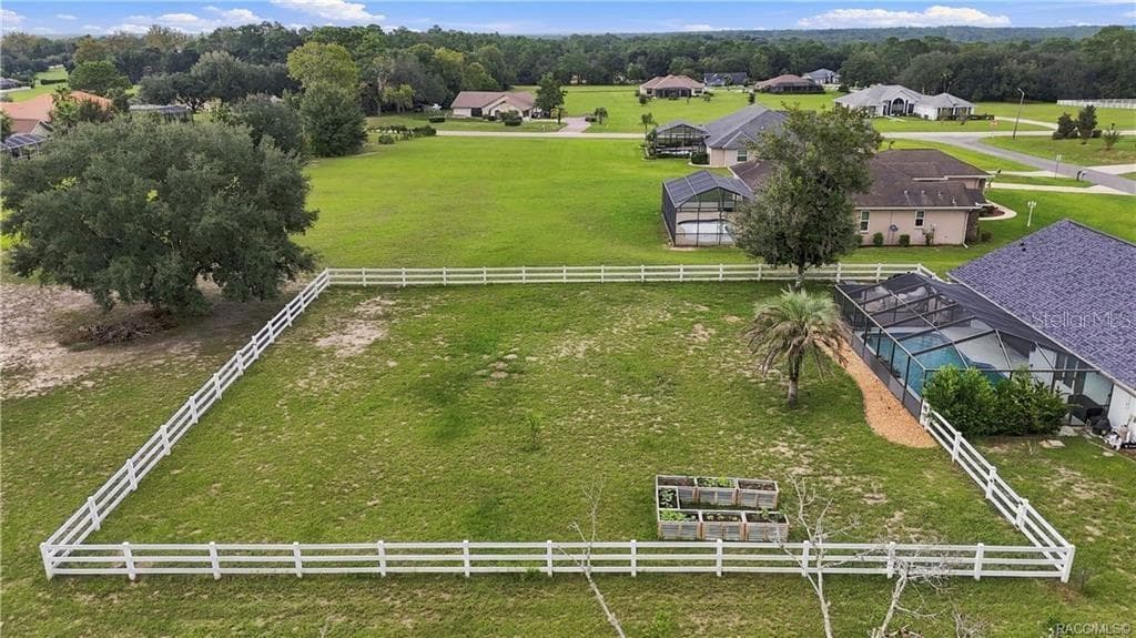 Aerial Backyard View – Take in the spacious WHITE RAIL-FENCED BACKYARD, raised garden beds & SCREEN-ENCLOSED POOL, all surrounded by beautiful green space. A wonderful setting for enjoying the outdoors! - 1436 N CHERRY POP DR, HERNANDO