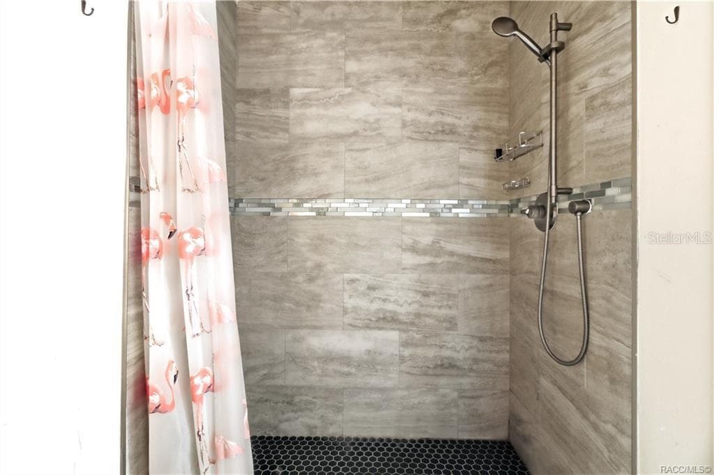Tiled Walk-In Shower – Beautifully finished WALK-IN SHOWER featuring floor-to-ceiling tile, decorative mosaic accent band, pebble-style shower flooring & handheld showerhead. - 6230 W GLEN ROBBIN CT, CRYSTAL RIVER
