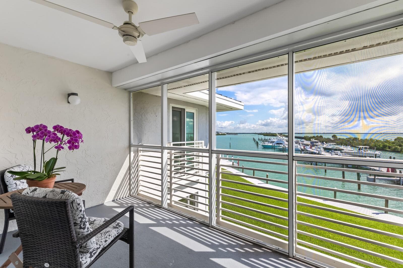 A cozy exterior screened porch with view of Gasparilla Sound and Uncle Henry's Marina - 5850 GASPARILLA RD #M4, BOCA GRANDE