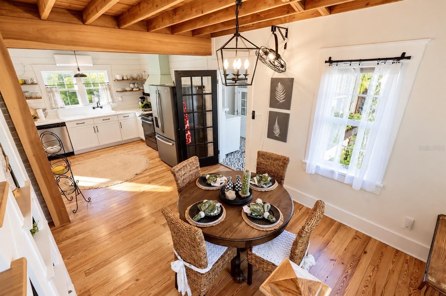 FARMHOUSE-STYLE DINING AREA featuring gorgeous exposed wood beam ceilings, beautiful wood flooring, a stylish lantern chandelier, and abundant natural light! OPEN TO THE BEAUTIFULLY UPDATED KITCHEN, creating a warm and inviting space for everyday dining and entertaining. - 1901 10TH ST, ST CLOUD