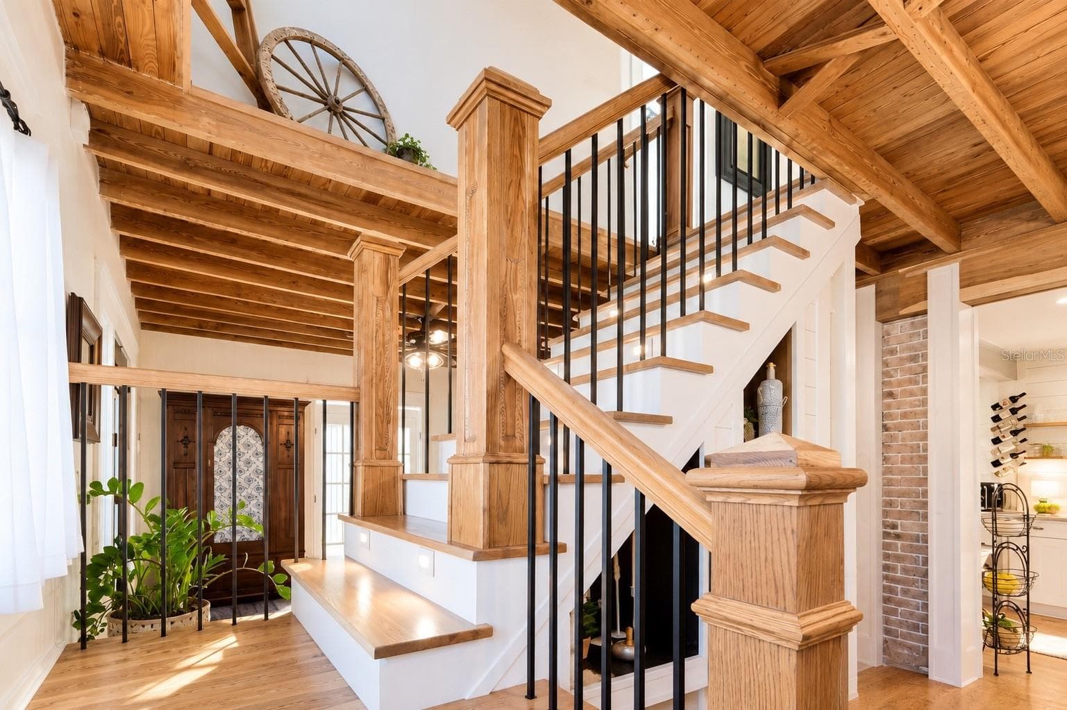 Beautiful custom wood staircase featuring rich wood posts and handrails, contrasting black iron balusters, and exposed wood beam ceilings that add warmth and architectural character throughout the home. - 1901 10TH ST, ST CLOUD
