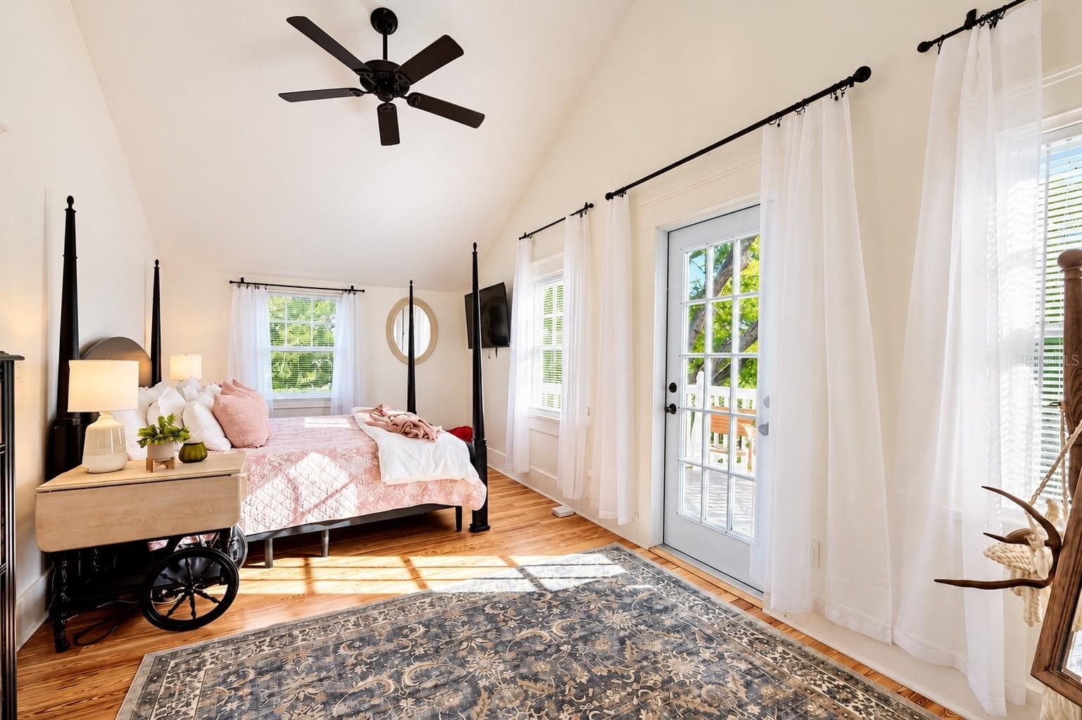 Bright and spacious bedroom featuring vaulted ceilings, beautiful hardwood floors, abundant natural light, and French doors leading to the outdoor deck. - 1901 10TH ST, ST CLOUD