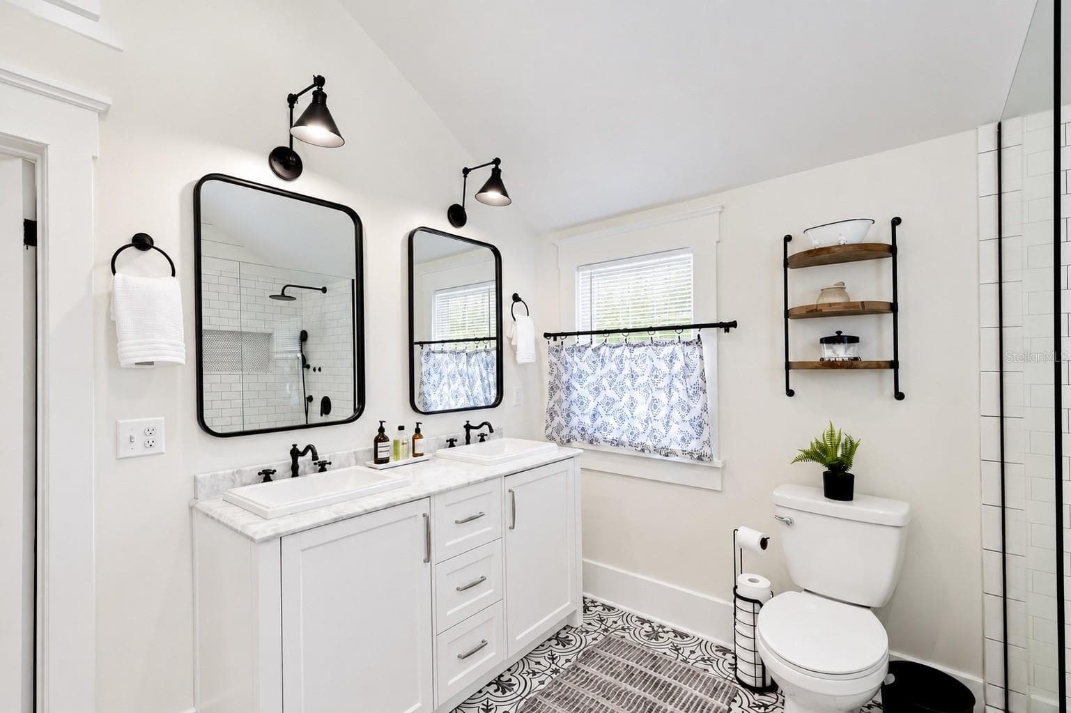 Beautifully updated upstairs bathroom featuring a spacious DOUBLE-SINK VANITY with marble-look countertops, stylish black fixtures, individual mirrors and lighting, ample cabinet storage, and gorgeous patterned tile flooring. Conveniently located between both upstairs bedrooms. - 1901 10TH ST, ST CLOUD