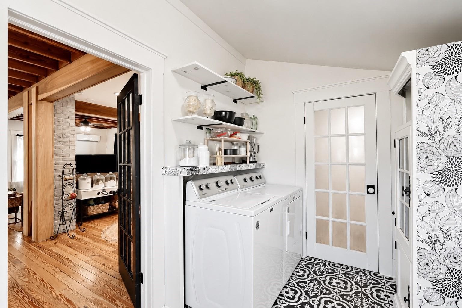 Conveniently located just off the kitchen, this charming INDOOR LAUNDRY ROOM features a washer and dryer, EXTRA OPEN SHELVING for storage and organization, and beautiful patterned tile flooring. A lovely glass-paneled door leads directly into the FULL DOWNSTAIRS BATHROOM, offering easy access to the fenced backyard and barn! - 1901 10TH ST, ST CLOUD
