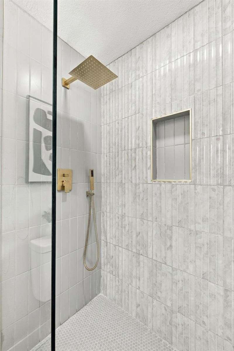 Beautiful Gold hardware with rainfall shower head and hand shower, shower niche and seamless glass entry - 1613 GREENWOOD DR, DUNEDIN