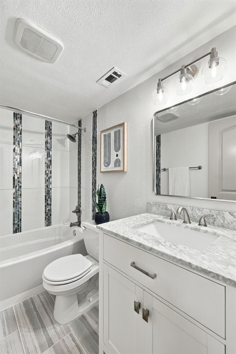 Hall bathroom with Marble vanity and updated shower/tub combo - 1613 GREENWOOD DR, DUNEDIN