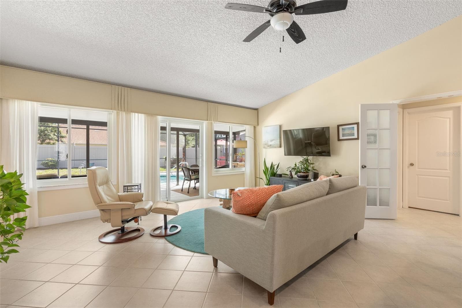 A cozy retreat for movie nights or quiet afternoons, this sunlit living room offers comfortable surroundings, generous windows, and sliding glass doors that lead directly to your poolside escape. - 19 EDGELY LN, PALM COAST