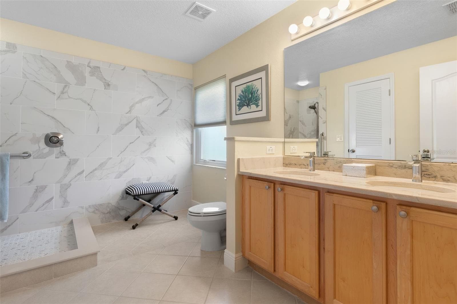 Remodeled in 2021, the primary ensuite brings a touch of spa-inspired luxury to everyday living, featuring a beautifully tiled walk-in shower, dual vanities, and elegant finishes that make getting ready a pleasure. - 19 EDGELY LN, PALM COAST