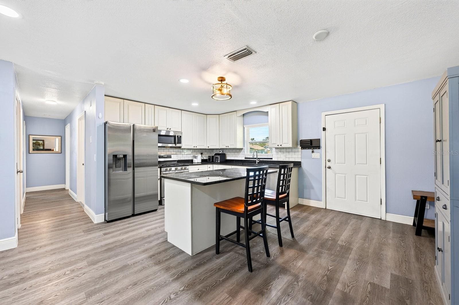 The Kitchen offers plenty of SOLID WOOD WHITE CABINETRY, solid-surface countertops and a center island with breakfast bar seating. - 1444 KENNY CT, WINTER GARDEN